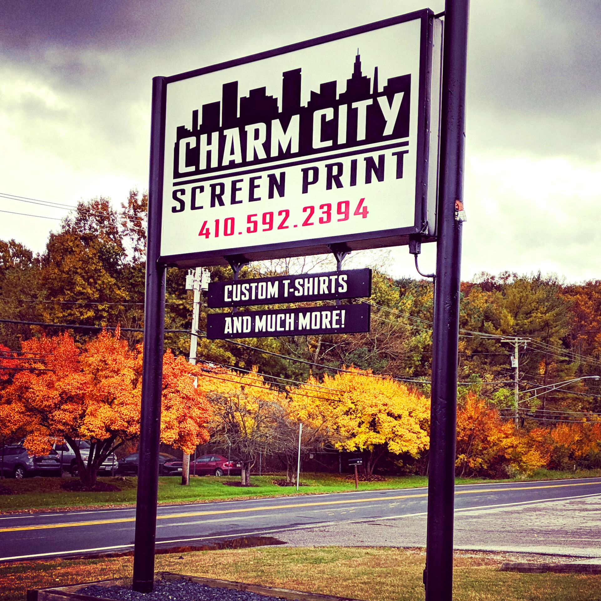 Vignette shot of the Charm City Screen Print outdoor sign next to a two-lane road